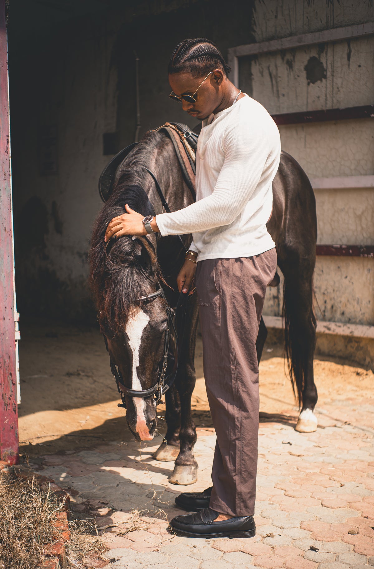 LORËVEN Drift Stretch Trouser in Anchor Charcoal — man in a white long-sleeve sweater standing with a horse in a rustic stable
