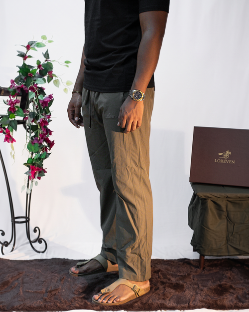 LORËVEN Drift Stretch Trouser in Mouse Brown — close-up of the drawstring trousers and black t-shirt with brown sandals against a white studio backdrop