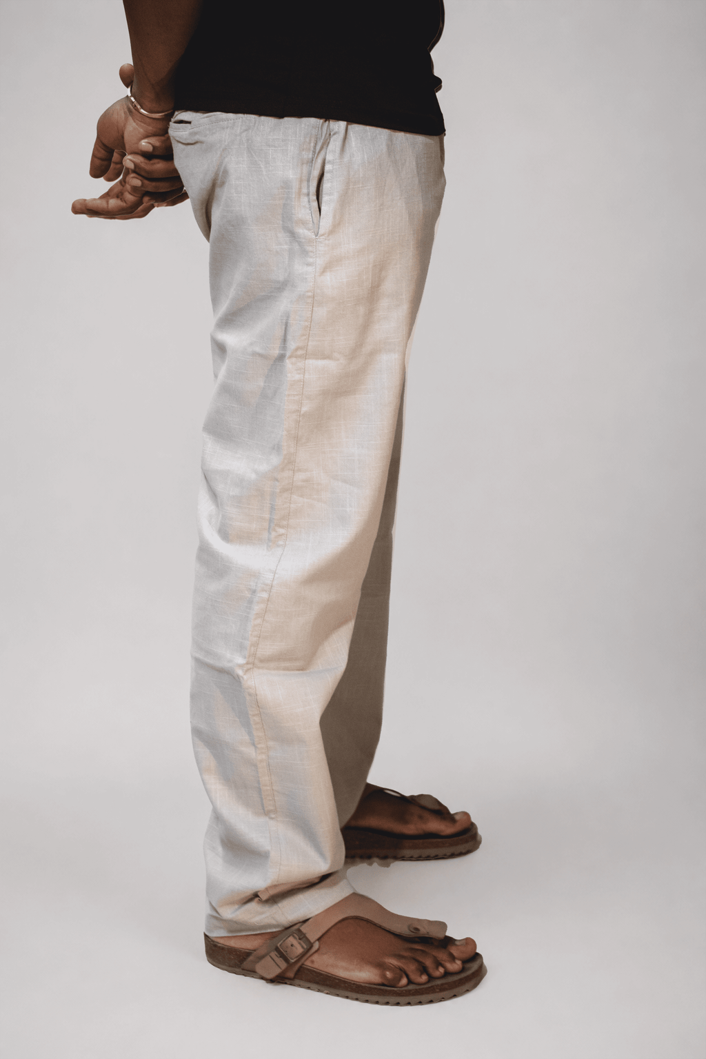 LORËVEN Linen Cotton Trouser in Silver Moon grey — waist-down detail shot of the trouser leg and drawstring waist, paired with brown leather slide sandals on a plain studio background