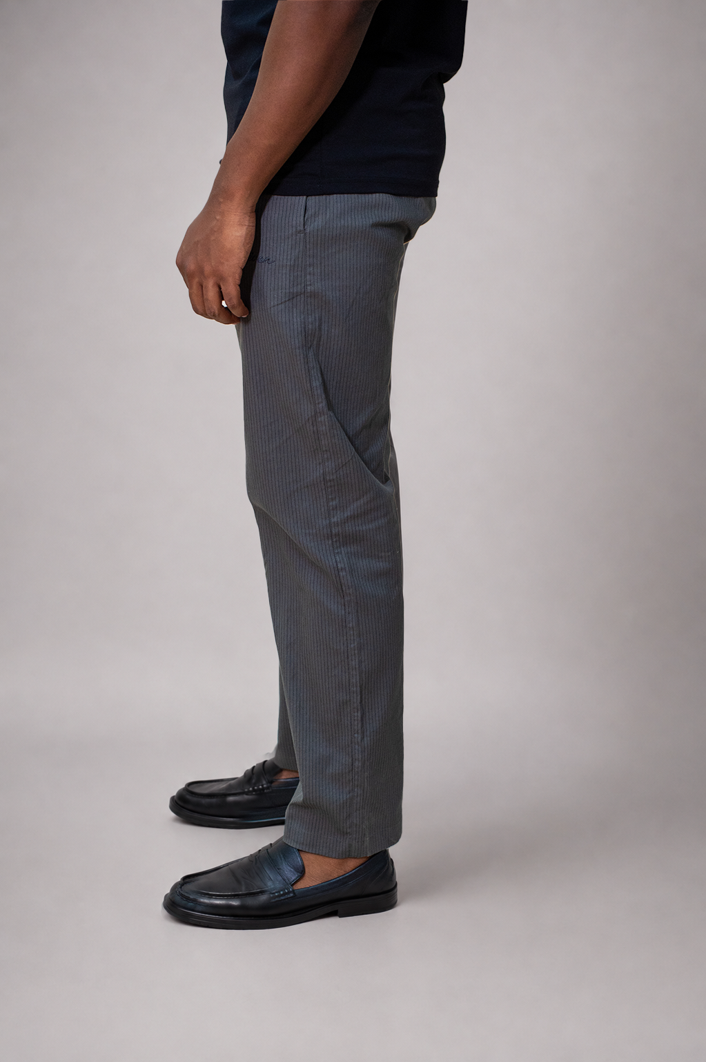 LORËVEN Striped Linen Trouser in Mediterranean Olive — close-up side profile of the trouser leg and black leather loafers against a neutral grey studio background